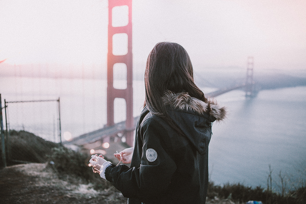 Woman standing on hill looking at the godlen gate bridge